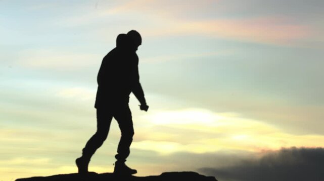 Man steps onto a rocky ledge and photographs nacreous, polar stratospheric clouds in Arctic Norway