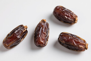 Fresh, natural, brown dates with wrinkled surface scattered on pure white background, highlighting plump texture, glossy sheen, and organic food concept for healthy eating.