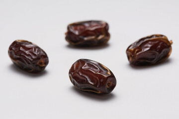 Fresh, natural, brown dates with wrinkled surface scattered on pure white background, highlighting plump texture, glossy sheen, and organic food concept for healthy eating.