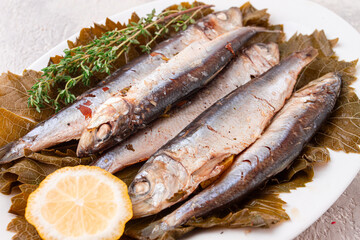 baked fish, in grape leaves, with spices, on a white plate, homemade,