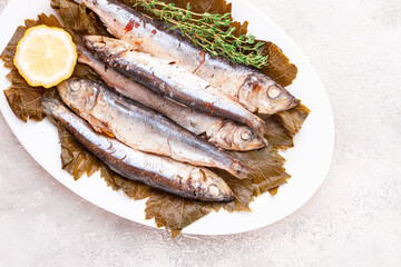 baked fish, in grape leaves, with spices, on a white plate, homemade,
