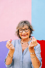Happy senior woman showing joy with hands on a vibrant wall