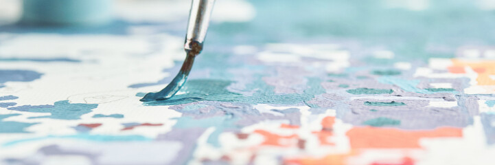 Naklejka premium Close-up of a brush with blue paint on canvas in an abstract colorful art expression.