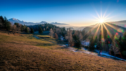 Sunrise over misty mountains and snow-dusted forest.