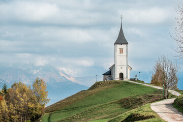 Church on a grassy hill with mountains in the background.