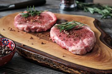 Close-up of two pieces of raw marbled beef steak on wooden cutting board.