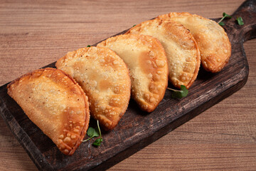fried chebureks, deep-fried, mini, on a chopping board, wooden table, close-up, no people,