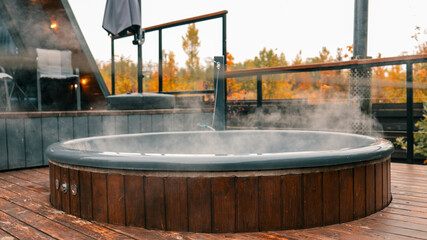 Outdoor hot tub with steam on a wooden deck in a natural setting