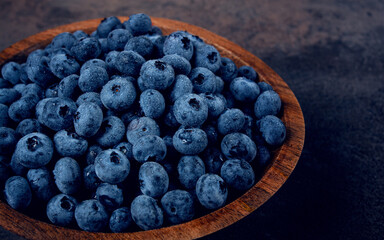 fresh blueberries, in a wooden bowl, on the table, top view, close-up, no people,