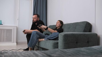 Relaxed young couple bonding while playing video games together, seated comfortably on living room sofa, sharing enjoyable moment of connection through digital entertainment - Powered by Adobe