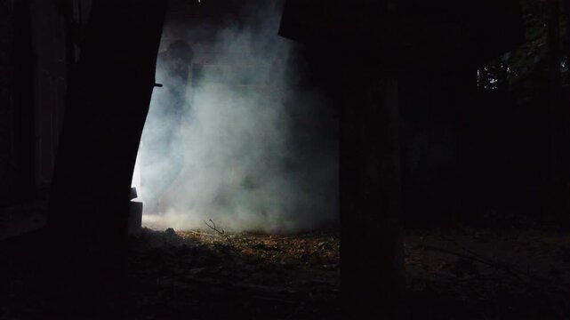 A zombie walking through a rustic cemetery graveyard with crosses and smoke. Classic suspense horror or Halloween film theme. 