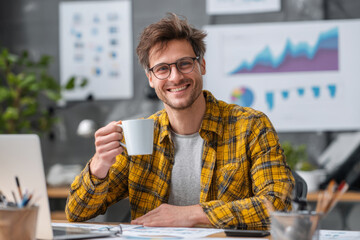 Man in glasses holding cup of coffee with computer monitors displaying charts