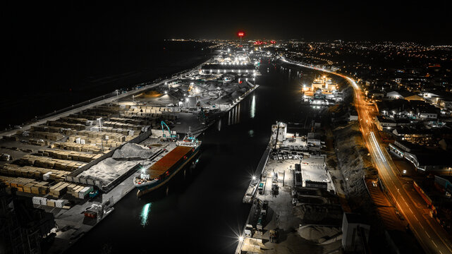 Illuminated cityscape at night showcases bustling port activity and coastal lights