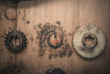 Old gears on a weathered wooden surface with signs of wear and use.