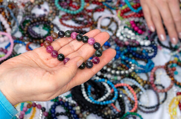 Hand holding colorful gemstone bracelet made of natural stone beads, handmade jewelry displayed at craft market or gemstone fair