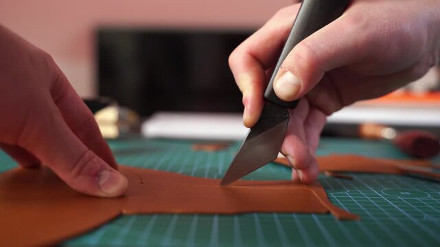 Craftsman carefully cuts leather with precision tools 4k video. Craftsman prepares leather pieces by cutting with precision, ensuring accurate templates. Cutting leather with knife.