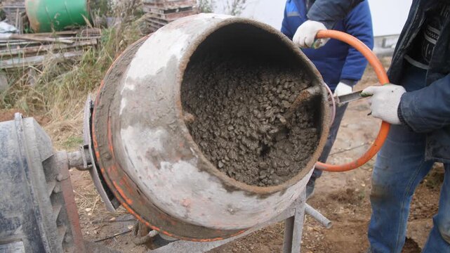 mixer operation closeup, operator manages concrete mixer carefully, closeup of operator adjusting mixer drum, operator carefully tilts mixer while ensuring consistent flow of concrete