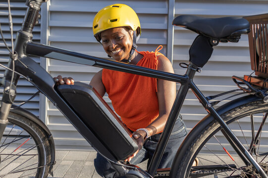Young African Woman changing battery on her electric bicycle