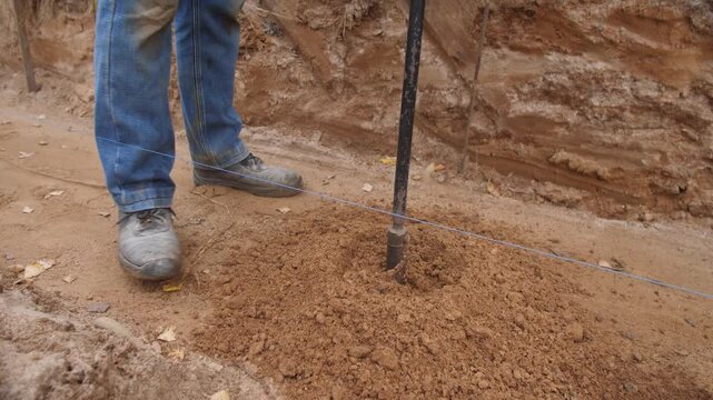 technician performs precise manual auger drilling, scientist skillfully drills test hole with careful footing, technician meticulously uses manual auger to expose soil layers scientifically