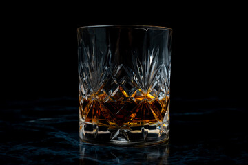 Lowball whisky glass in dark studio environment on dark marble table
