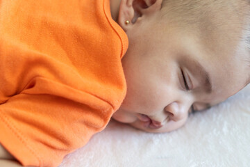 Sleeping baby wearing orange shirt resting peacefully