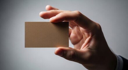 Business card held by a person in a suit against a simple gray backdrop