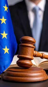 Wooden judge gavel with European Union flag and legal book in courtroom symbolizing justice law with serious atmosphere and person in suit background