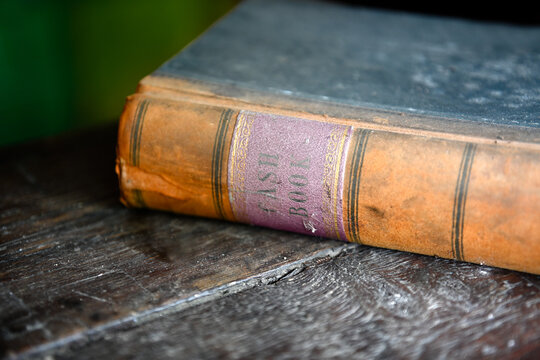 Closeup of vintage leather bound ledger book on an old wooden desk
