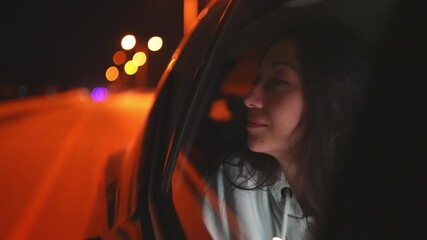 A girl looks out the window at night with a soft smile. The glow of city lights and shadows creates a peaceful, warm atmosphere, blending serenity with the quiet joy of night travel.