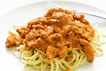 Chicken curry spaghetti with fork in a plate. Italian and Indian mixed dishes. Fusion food.