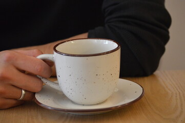 Person Holding Coffee Cup on Wooden Table