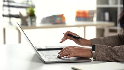 Workplace Focus: A focused professional, their hands gracefully dancing across a laptop keyboard and meticulously reviewing business documents, immersed in work - Powered by Adobe