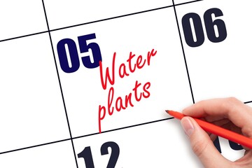 5 th day of the month.  Hand writing Water plants reminder  on calendar with red pen on white background. concept of plant care. Planning and scheduling
