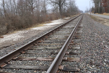Railway Track Curving Slightly Right toward Horizon with Bare Trees and Light Snow