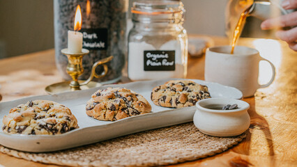 A white tray with three chocolate chip cookies and a mug of tea