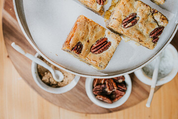 A plate of brownies with a pile of pecans next to it