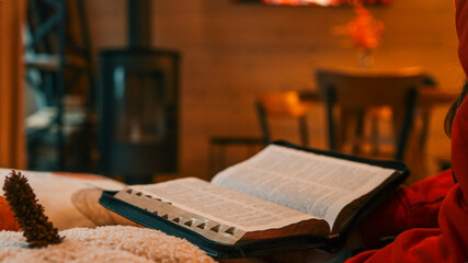 Open Bible on a Cozy Couch with a Fireplace in the Background