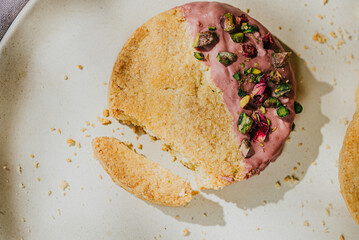 A cookie with a pink frosting and green sprinkles on top