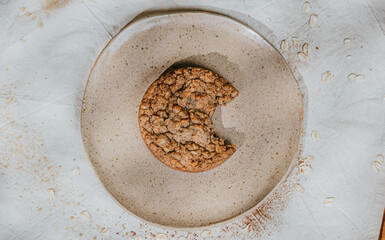 A cookie is on a white plate with a bite taken out of it