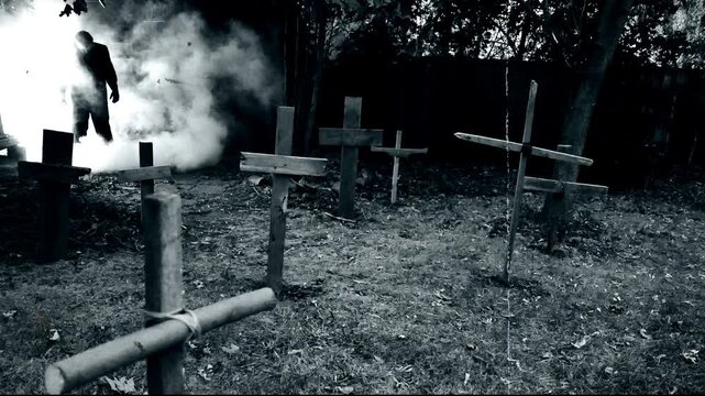 A zombie walking through a rustic cemetery graveyard with crosses and smoke. Classic suspense horror or Halloween film theme. Edited with vintage silent film effects.