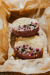 Two small pastries with pink frosting and green nuts on top