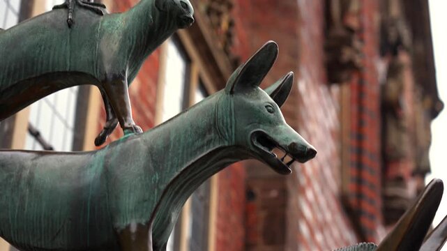 Close up detail of Bremen Town Musicians bronze statue showing rooster and cat figures against brick wall in Bremen Germany 