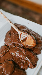 A spoon is scooping chocolate sauce from a pan