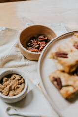 A plate of baked goods sits on a table with a bowl of nuts and a jar of sugar