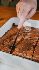 A person is cutting a brownie into pieces with a knife