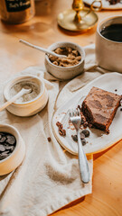 A plate of brownie with a fork on it sits on a table with a white cloth