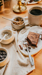 A plate of brownie with a fork on it sits on a table with a white cloth