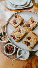 A plate of four peanut butter bars sits on a wooden table