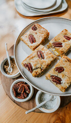 A plate of four peanut butter bars sits on a wooden table with four small bowls