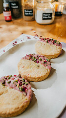 Three cookies with pink frosting and green sprinkles on top